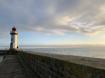 Lighthouse by sea against sky