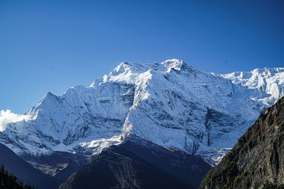 Scenic view of snowcapped mountains against clear blue sky