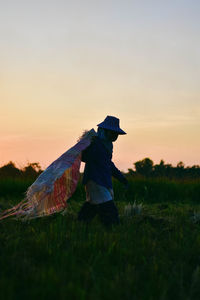 Senior woman with plastic walking on field during sunset