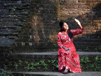 Portrait of woman standing against brick wall