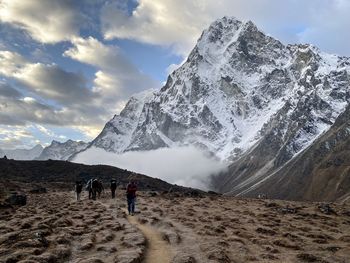 People walking on snowcapped mountain against sky