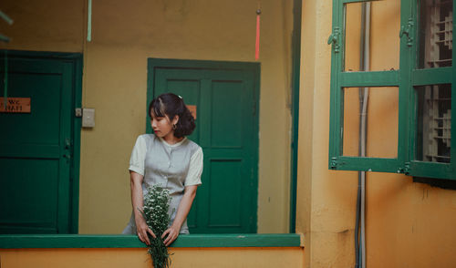 Woman with flowers standing in balcony