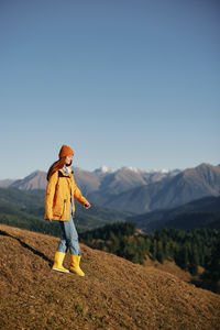Full length of woman standing on mountain against clear sky