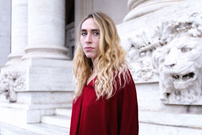 Portrait of young woman standing against building