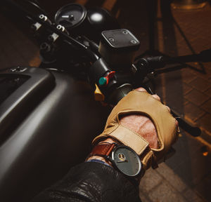 Cropped hand holding handlebar of motorcycle