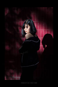 Portrait of woman standing against red curtain