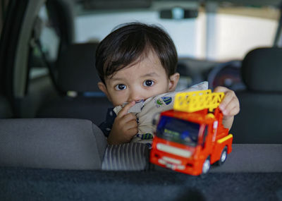 Portrait of cute boy playing with toy truck in car