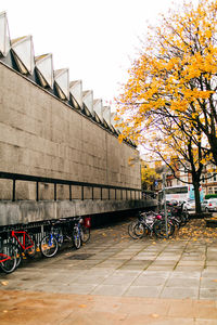 Bicycle parked by railing in city during autumn