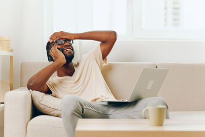 Man using laptop while sitting on sofa at home