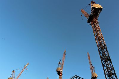 Low angle view of crane against clear blue sky