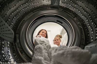 Portrait of mother and daughter removing clothes from machine