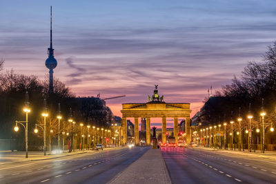 The famous brandenburg gate in berlin with the television tower before sunrise
