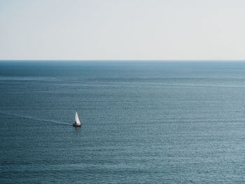 Sailboat sailing in sea against clear sky