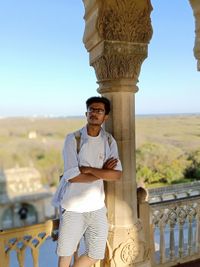 Portrait of young man standing against railing