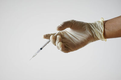 Close-up of hand holding paper over white background