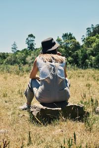 Rear view of woman sitting on field against clear sky