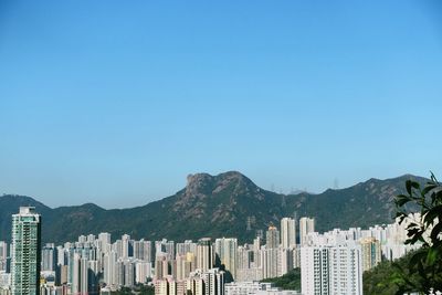 Buildings in city against clear blue sky