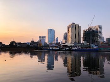 Reflection of buildings in city at sunset