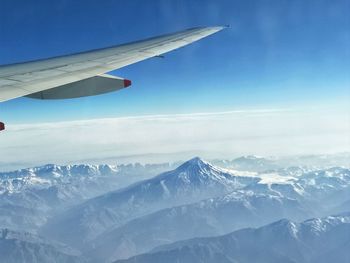 Airplane flying over snowcapped mountains against sky