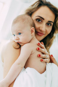 Mother carrying shirtless son at home