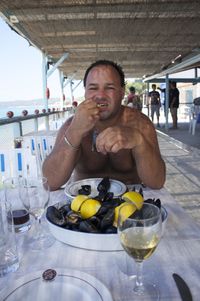 Shirtless man eating seafood at restaurant
