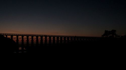 Silhouette bridge against clear sky during sunset