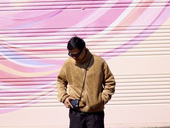 Young man standing against wall