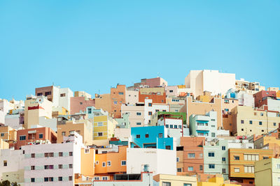 From below of residential houses located on street of town against cloudless blue sky in canary islands