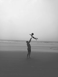 Side view of man playing with daughter at beach