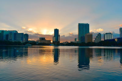 Buildings by swimming pool against sky during sunset