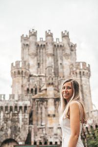 Portrait of smiling young woman standing against building