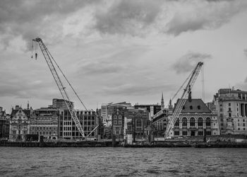 Cranes by river against sky