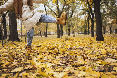 Woman kicking autumn leaves at park