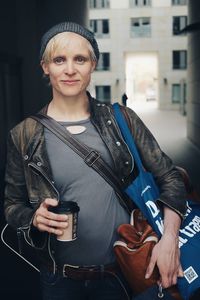 Portrait of smiling young woman holding camera