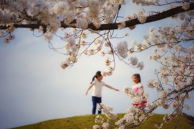 Low angle view of girl standing against tree