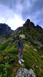 Rear view of man standing on mountain against sky