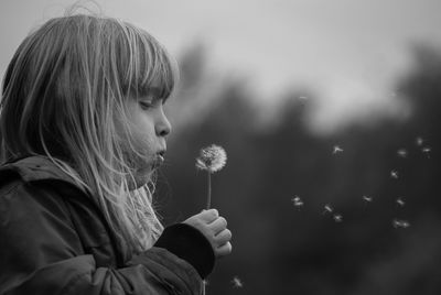 Close-up of cute girl blowing dandelion