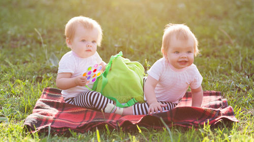Sisters playing with toys while sitting at lawn