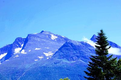 Low angle view of snowcapped mountain against clear blue sky