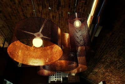 Close-up of illuminated light bulb hanging from ceiling