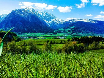 Scenic view of green landscape and mountains against sky
