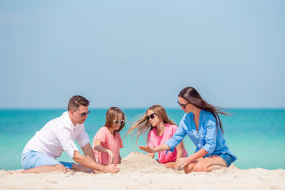 People sitting on beach against clear sky