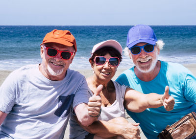 Portrait of friends gesturing while sitting at beach