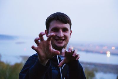 Portrait of happy man imitating as animal against sky