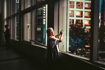Full length of woman standing by window in city