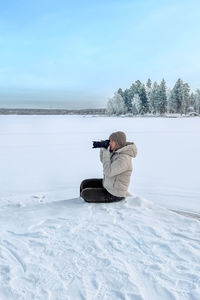 Rear view of man skiing on snow covered field against sky