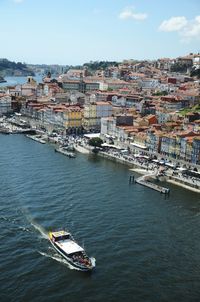 High angle view of sailboats in sea by buildings against sky