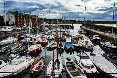 Boats moored at harbor against sky