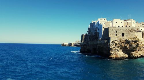 Sea by buildings against clear blue sky