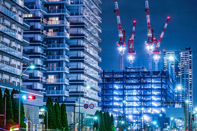 Illuminated modern buildings in city against sky at night